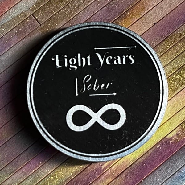 The back side of the same coin. The words Eight years Sober are written in different fonts in the styling of the game. There is a large infinity sign in the center of the chip.